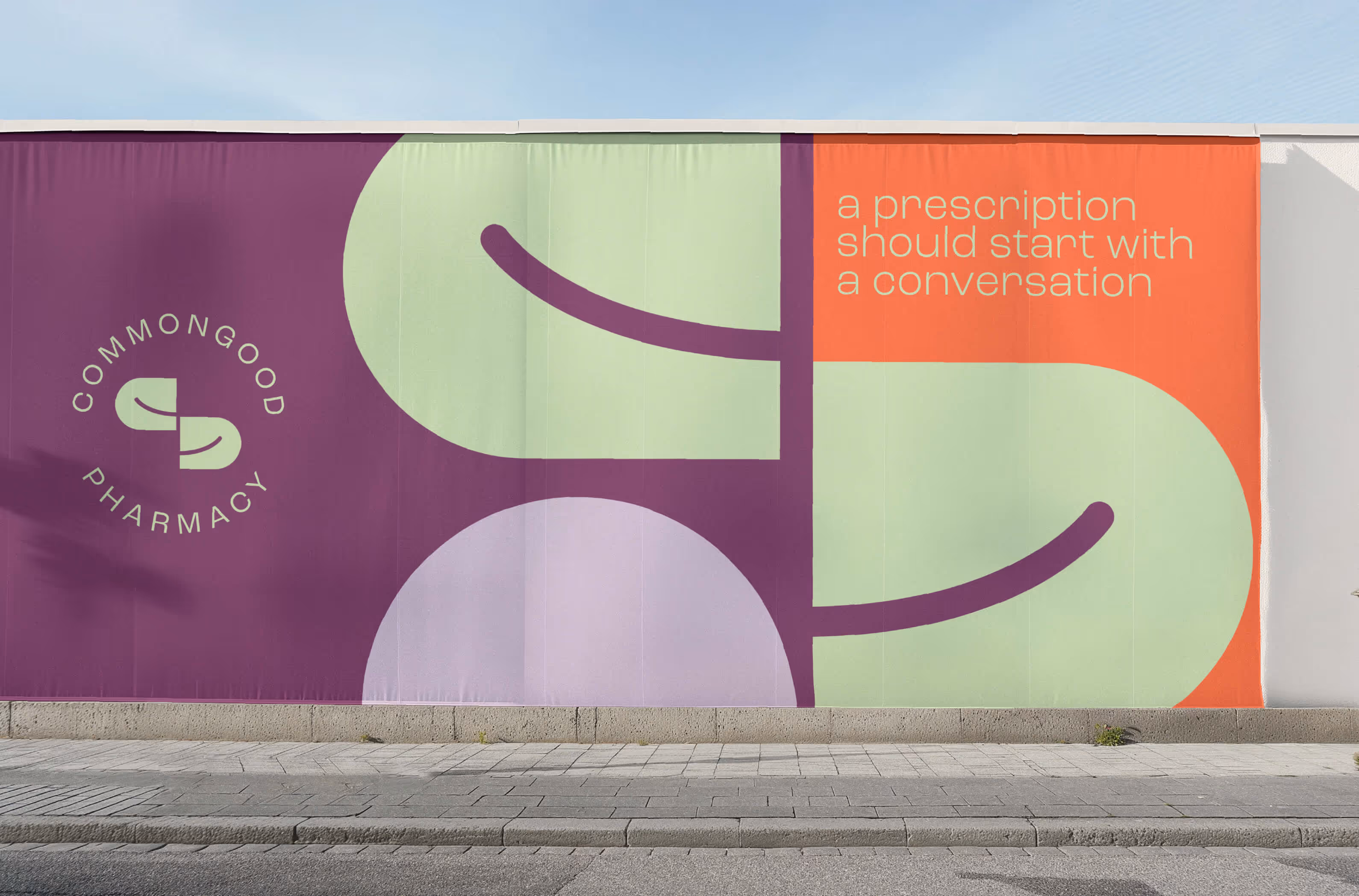 A colourful street-level billboard along side a walkway that showcases the common good brand.