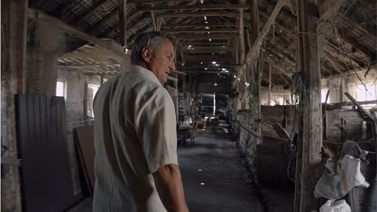 An image of a an older Romanian man walking through his barn.