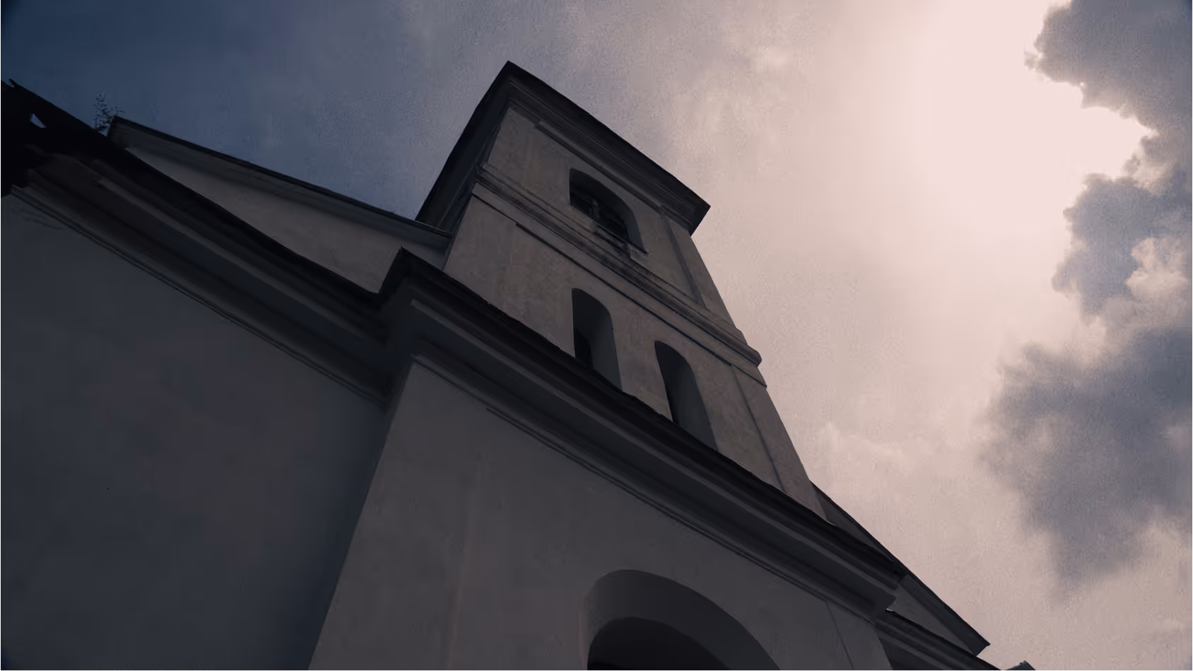 A upward looking image of a church steeple with a cloudy sky in the background.