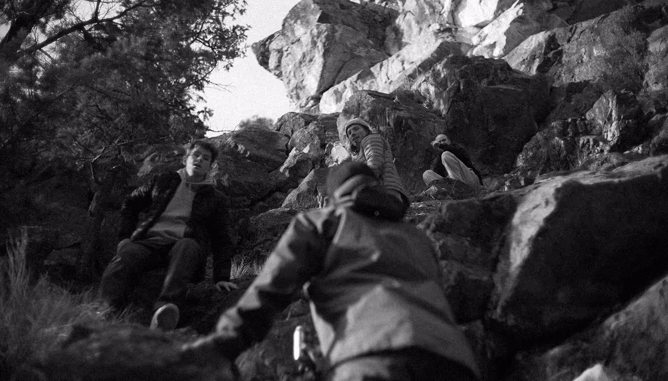 A black and white image of some mens scaling a cliff. 