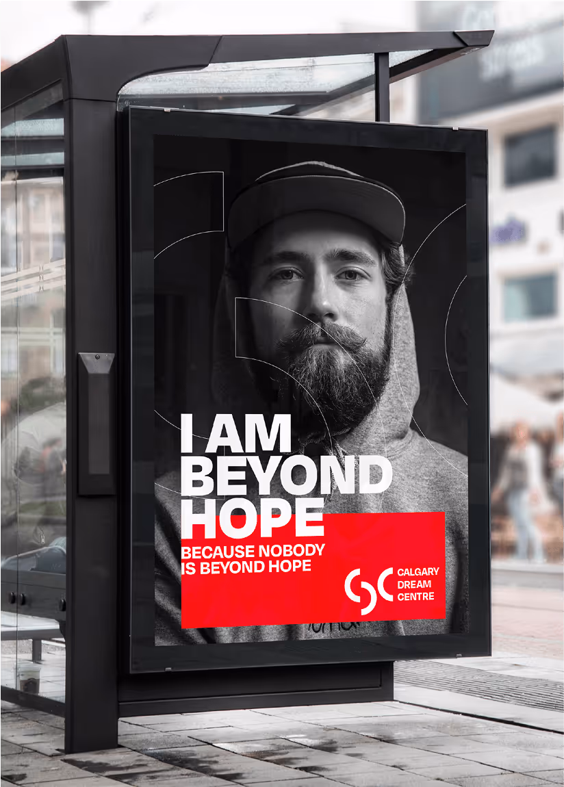 Bus shelter advertisement showing a bearded man in a hoodie with the text ‘I AM BEYOND HOPE because nobody is beyond hope’ and the Calgary Dream Centre logo.