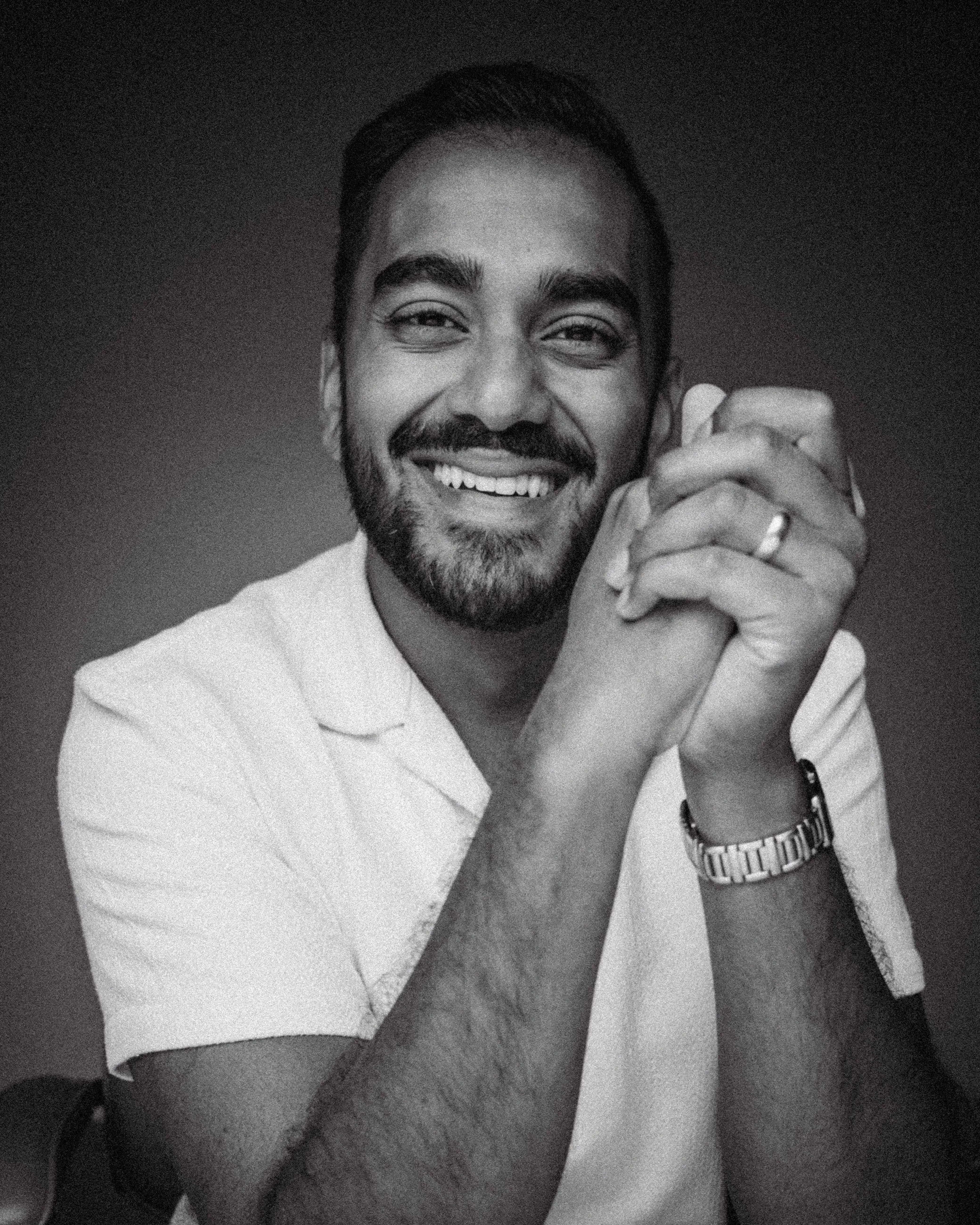 A black and white image of a bearded man smiling