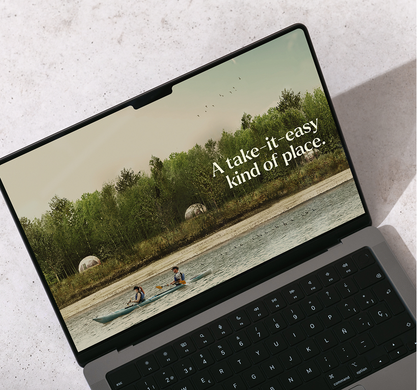 Laptop screen showing two people kayaking on a river near a forest with the text 'A take-it-easy kind of place.'