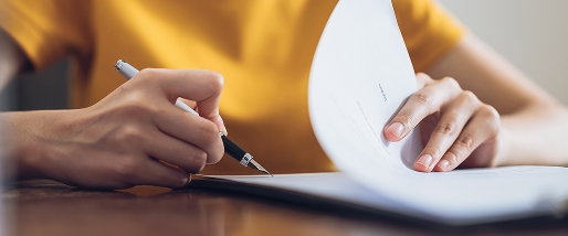 Close-up of the hands of a woman signing a document