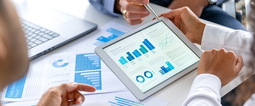 close-up of three people looking at an iPad with charts and graphs
