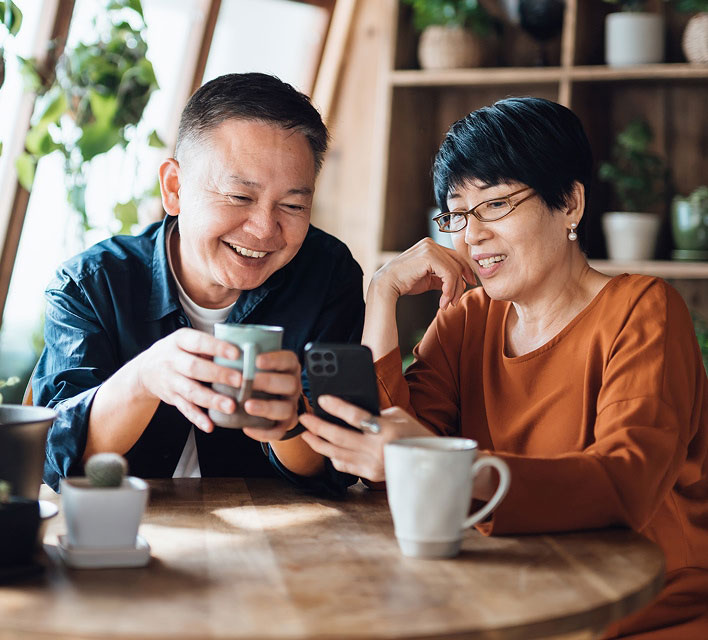 man and woman drinking coffee and looking at a mobile phone