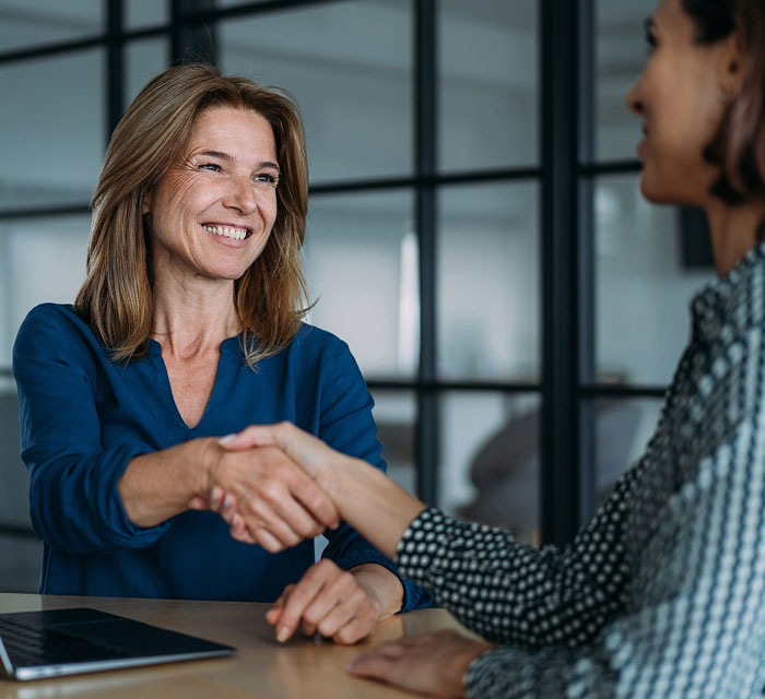 two women shaking hands at a table