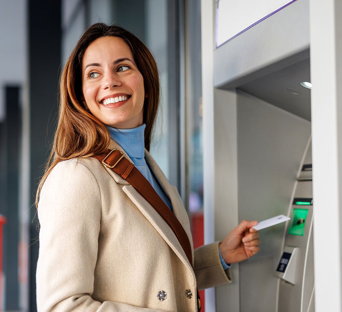 woman smiling, standing at an ATM