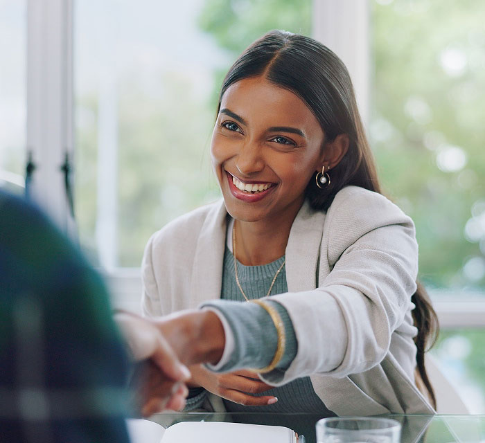 woman smiling and shaking hands with person out of frame