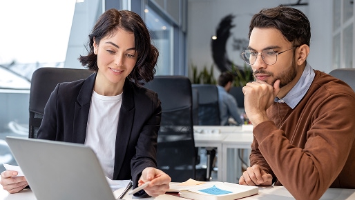 woman and man looking together at paperwork and a laptop