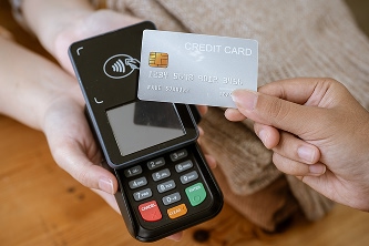 Close-up of a person tapping their credit card on a contactless payment device