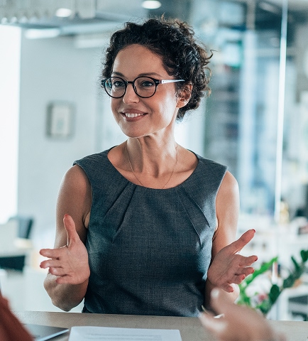 woman in business attire gesturing and smiling while talking