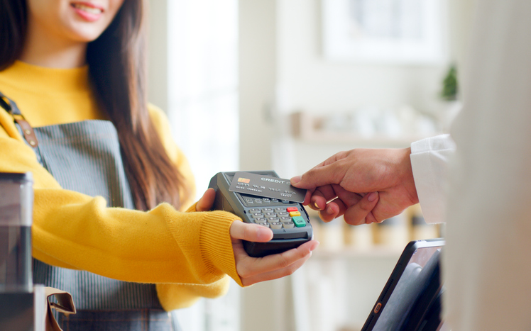 close-up of person tapping credit card on payment device