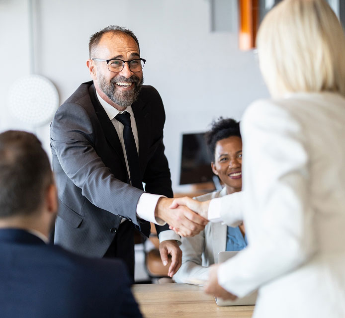 man standing and smiling while shaking hands with a woman