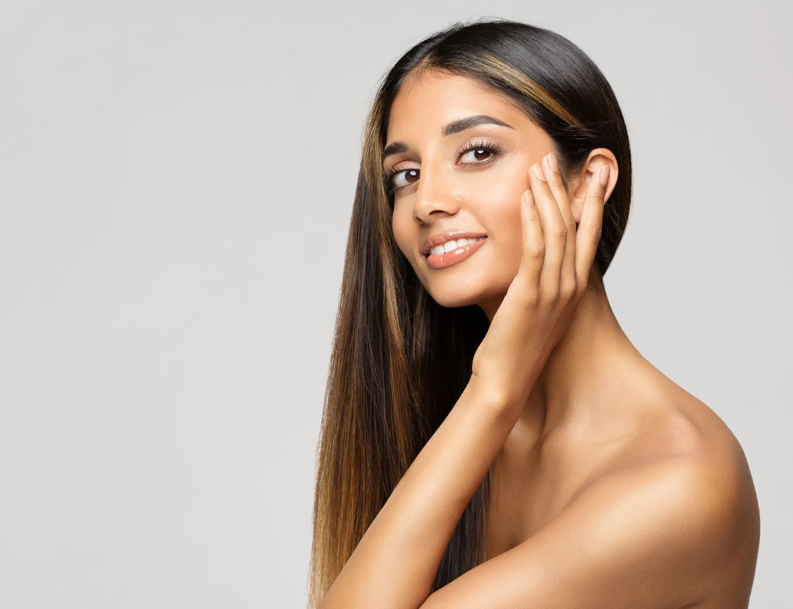 tan woman touching cheekbone