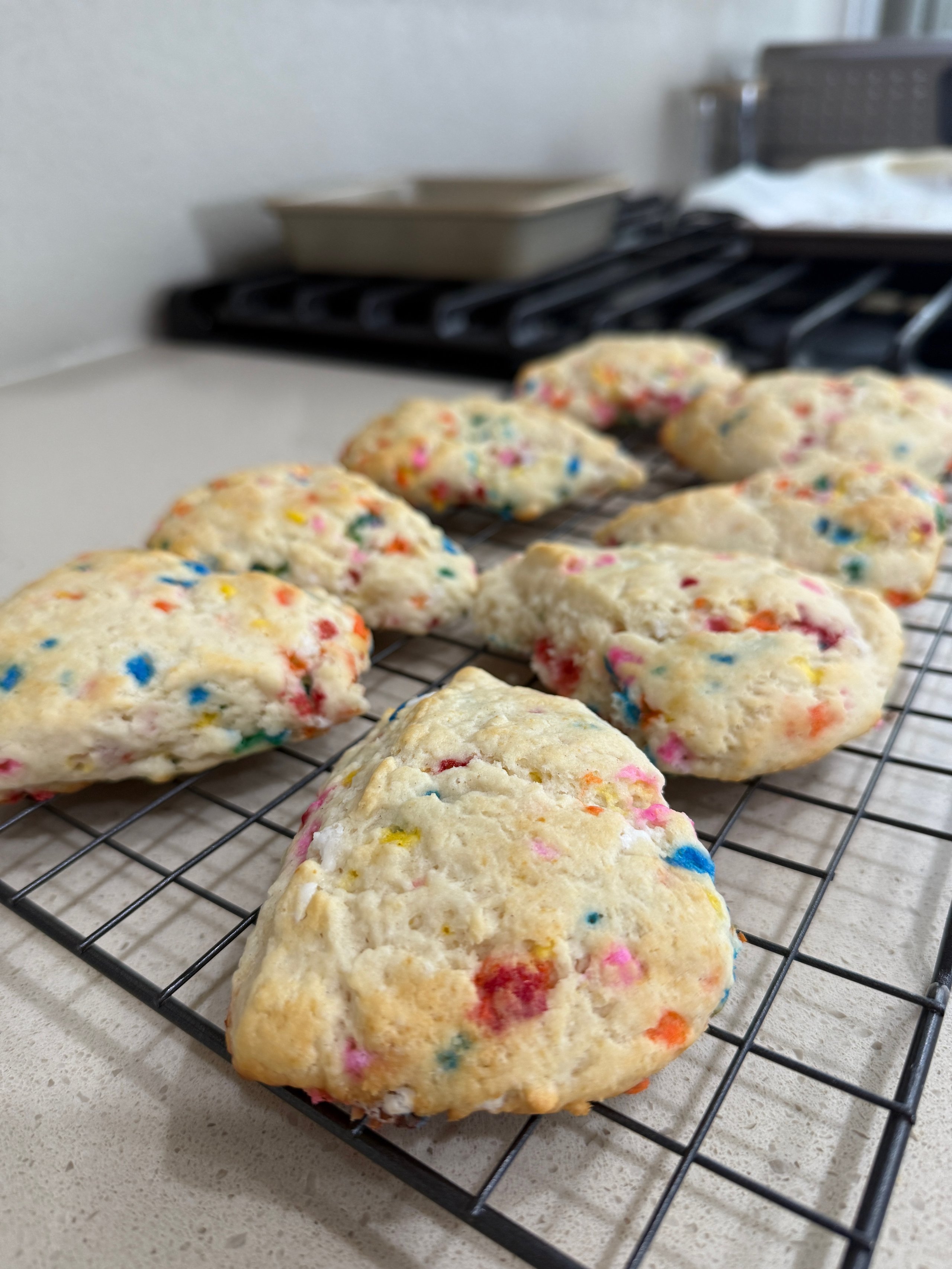 Colorful funfetti cookies cooling on a wire rack near a stovetop