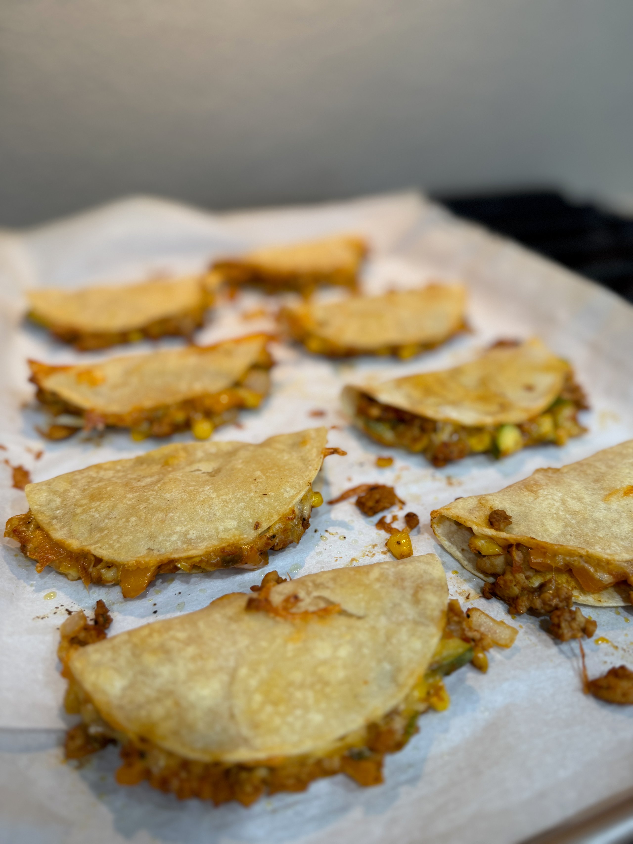 Crispy golden mini tacos or quesadillas on parchment paper
