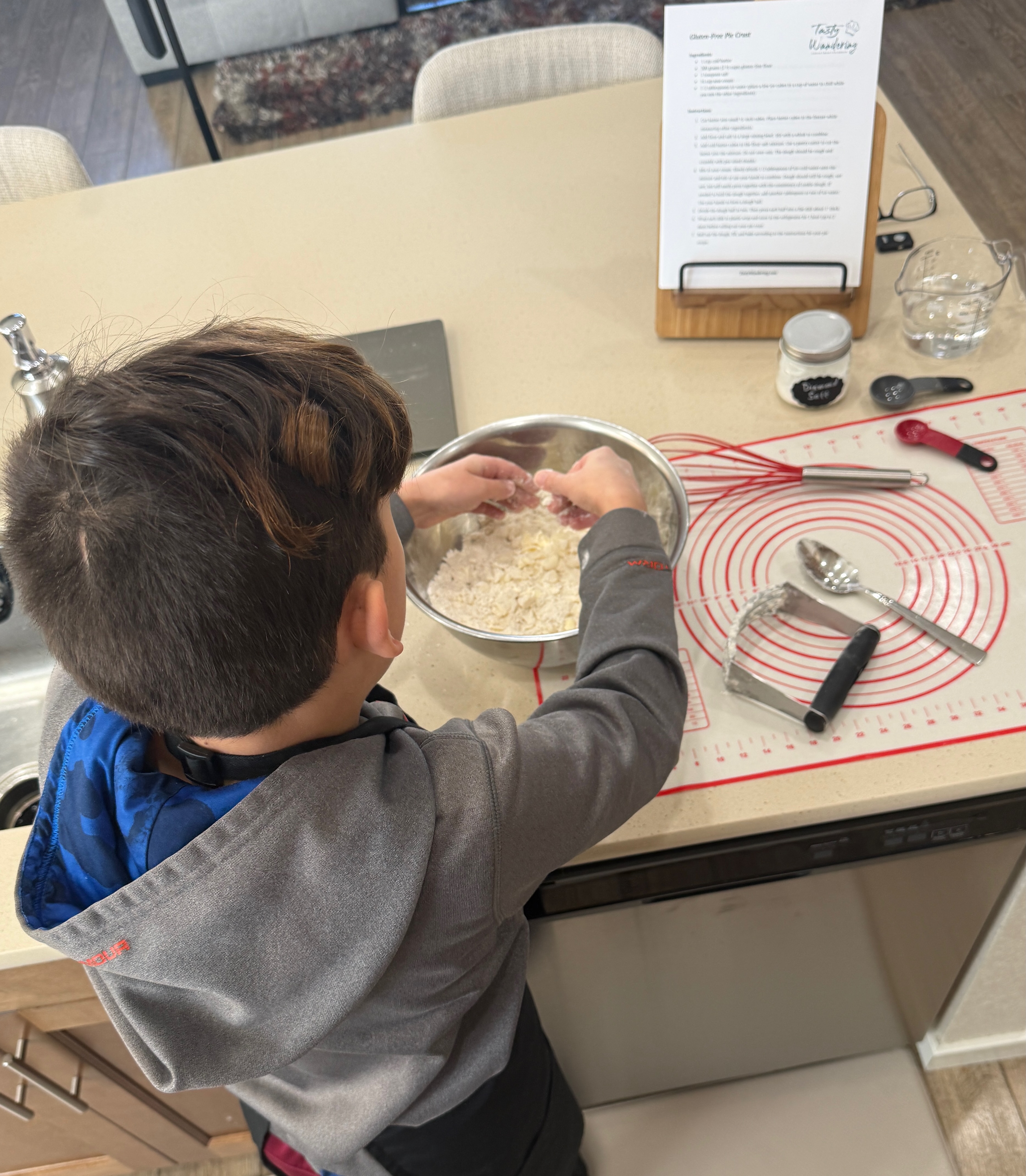 Child mixing ingredients on kitchen counter with baking tools nearby