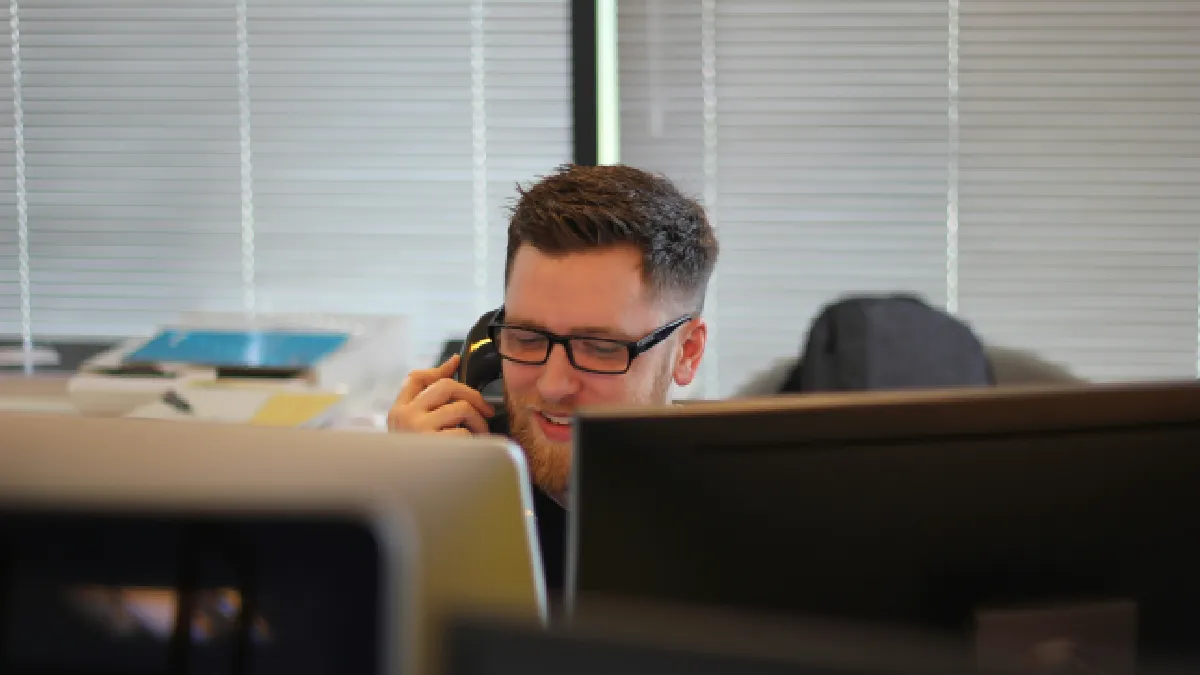 Employee speaking by phone in an office, showing why EAPs alone are not enough to support mental health