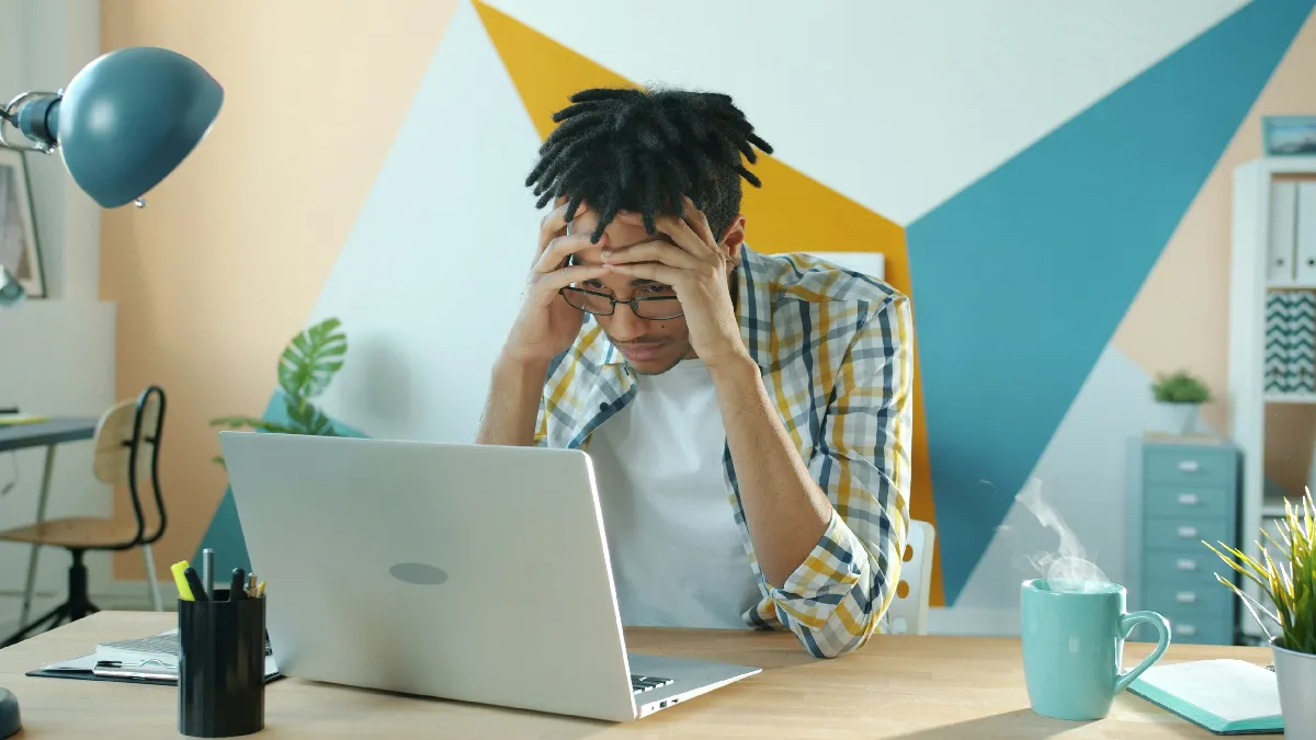 Stressed employee at a laptop, illustrating the impact of AI on workforce wellbeing for HR leaders