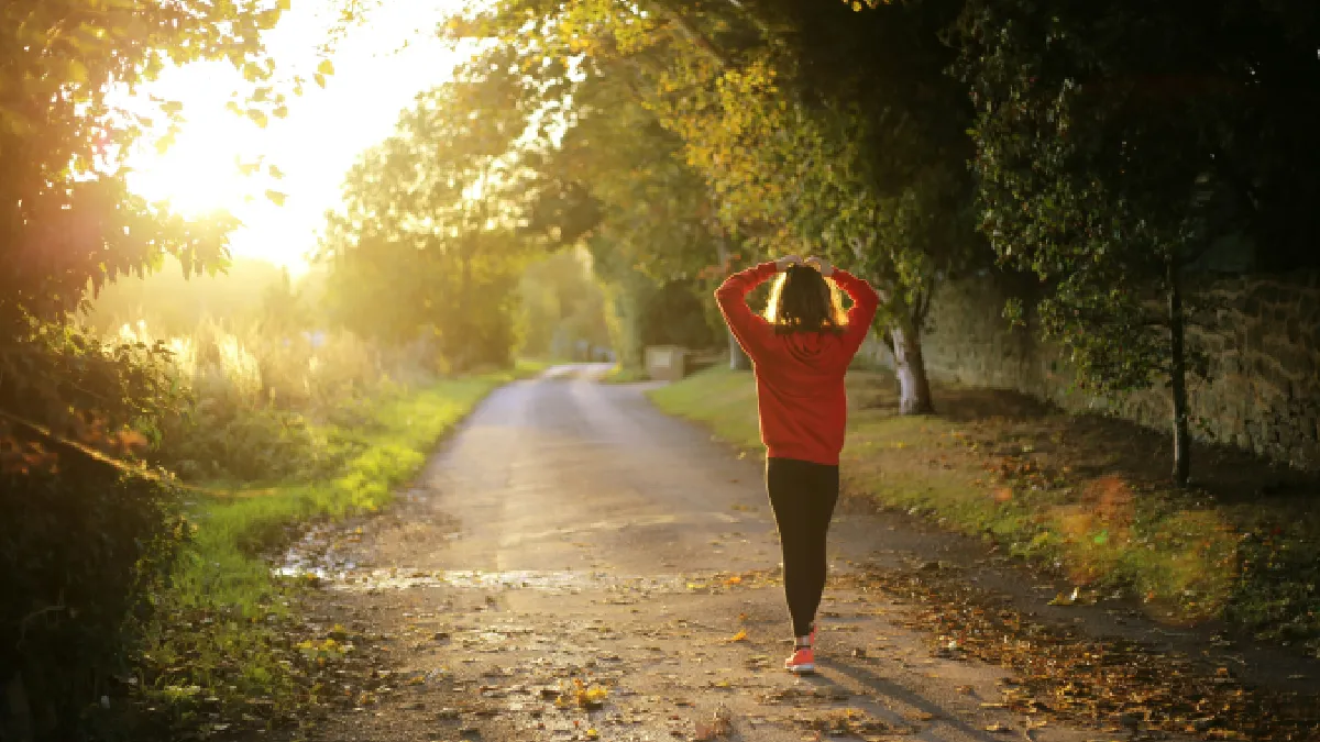 Woman walking outdoors at sunset, showing movement as medicine for better mental health