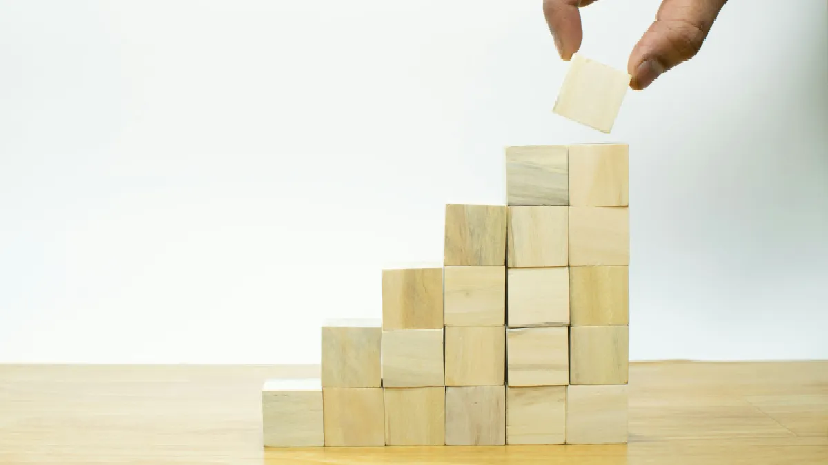 Hand stacking wooden blocks, symbolising self-management as a core leadership issue