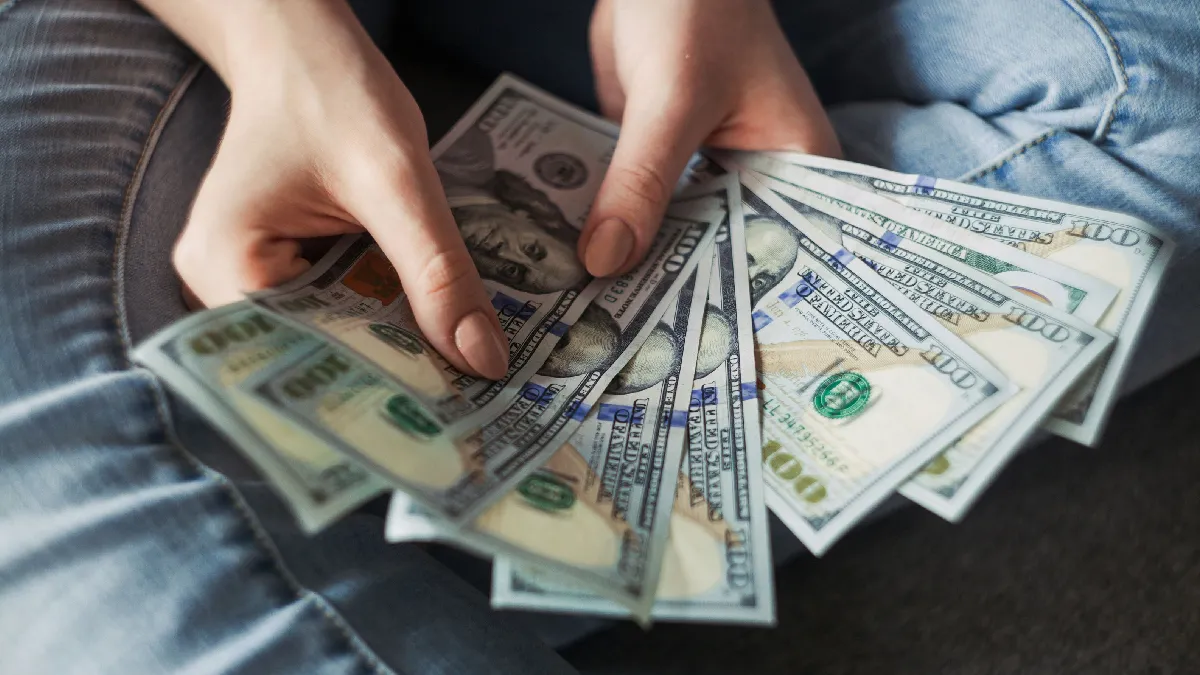 Person holding cash, representing how to pick stocks properly when choosing individual investments