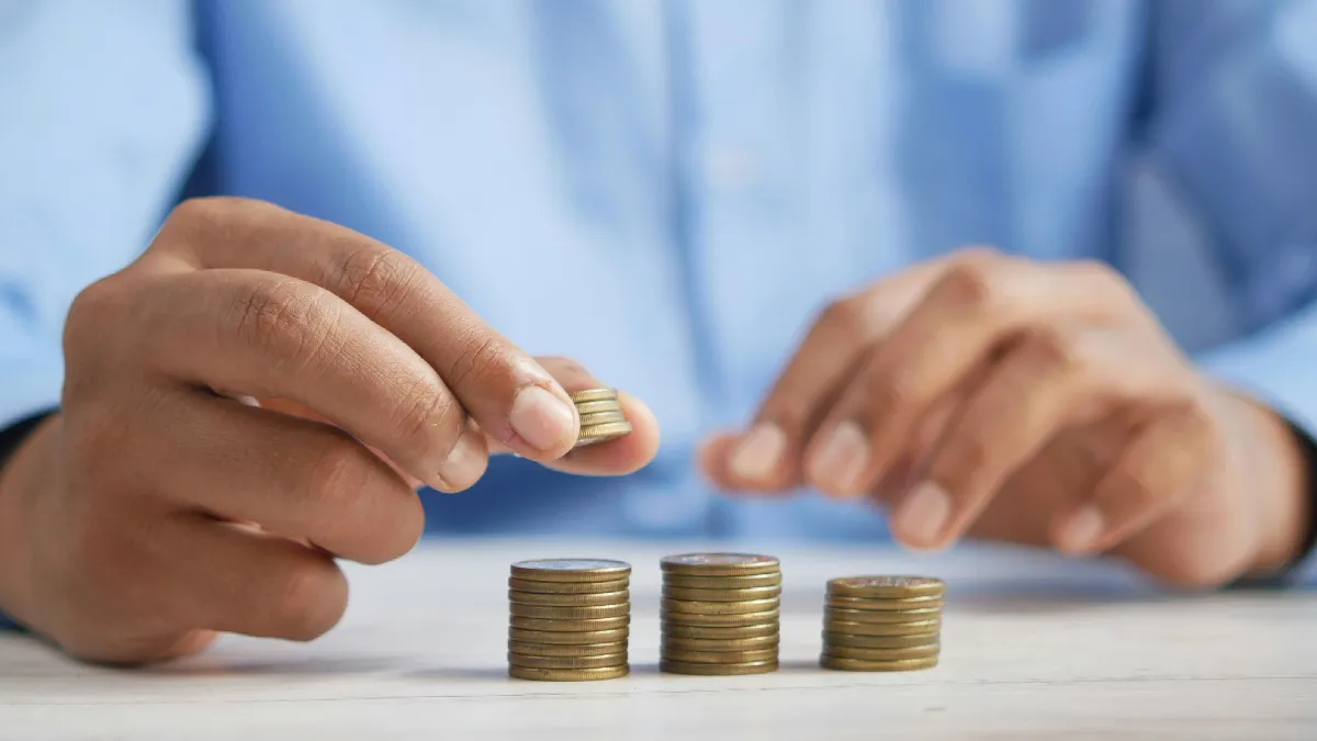 Person stacking coins to illustrate how capital markets work and why boring investing wins