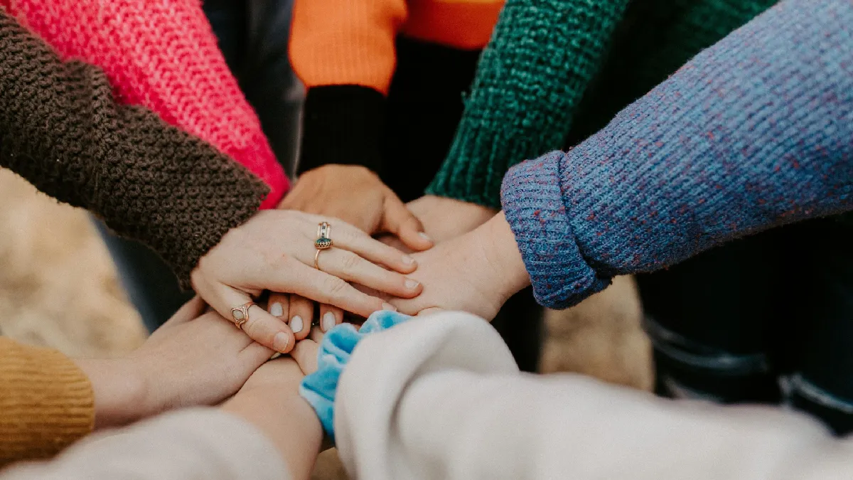 Colleagues stacking hands to show workplace belonging as a health indicator, not just a culture metric