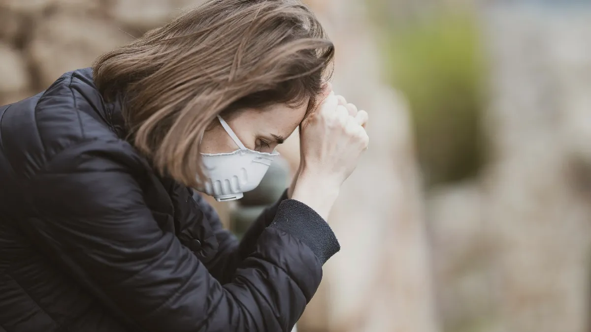 Unwell woman wearing a face mask, reflecting falling healthy life expectancy for UK and US employers