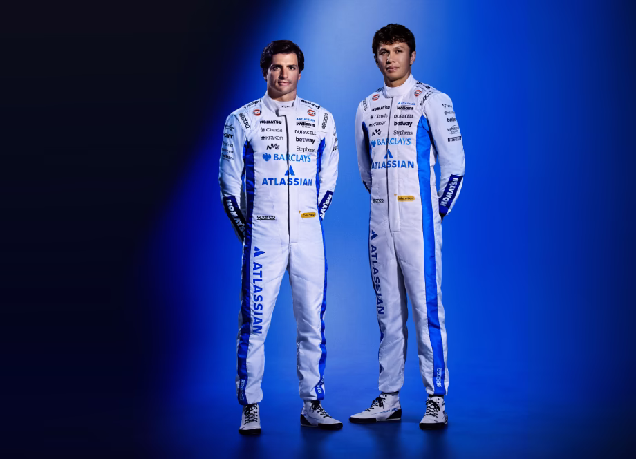 Full-body portrait of Williams F1 drivers Carlos Sainz and Alex Albon in their official white and blue racing suits.