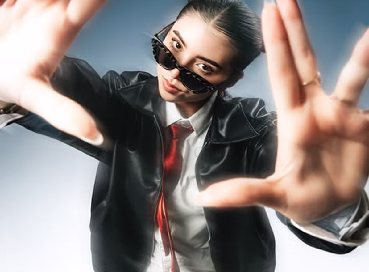 Frau mit Sonnenbrille, roter Krawatte und schwarzem Lederjackett, die die Kamera einrahmt.