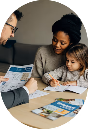 Une femme et une enfant regardent des plans tandis qu'un homme les leur montre dans un bureau.