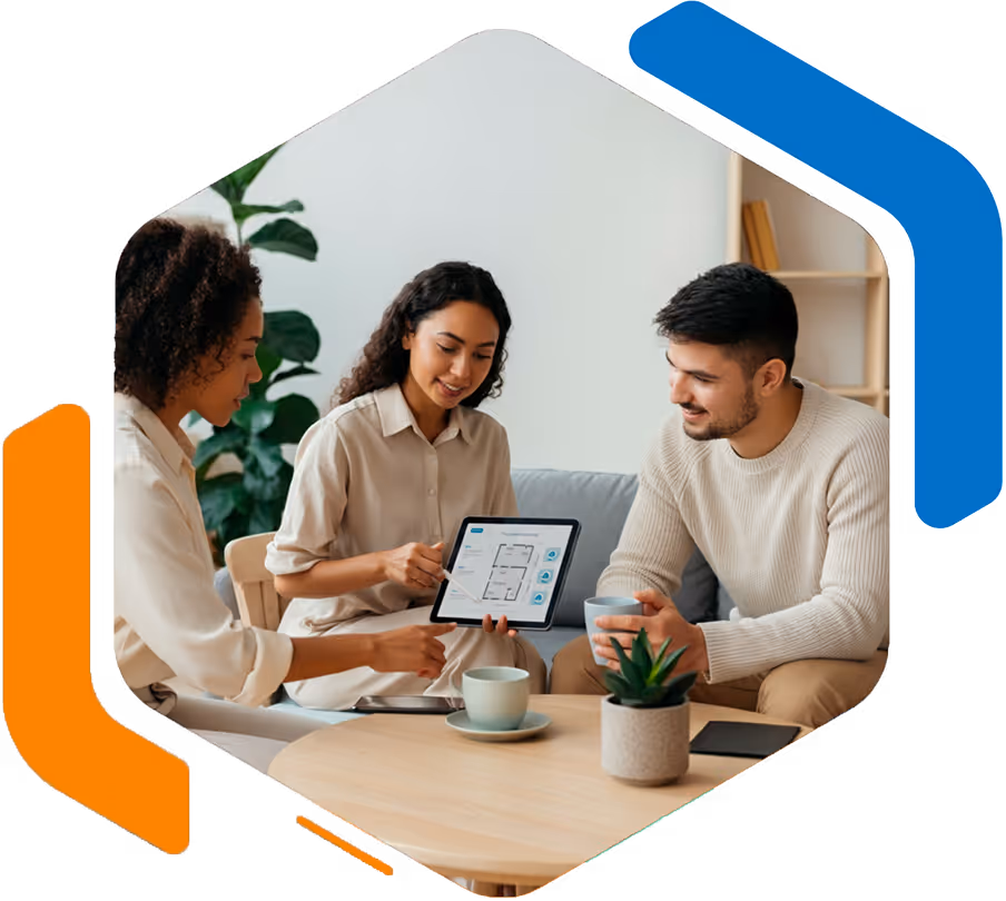 Trois personnes assises autour d'une table basse discutant d'un plan de maison affiché sur une tablette.