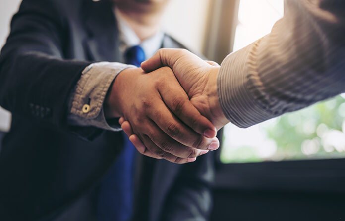 Two people in business attire shaking hands indoors.