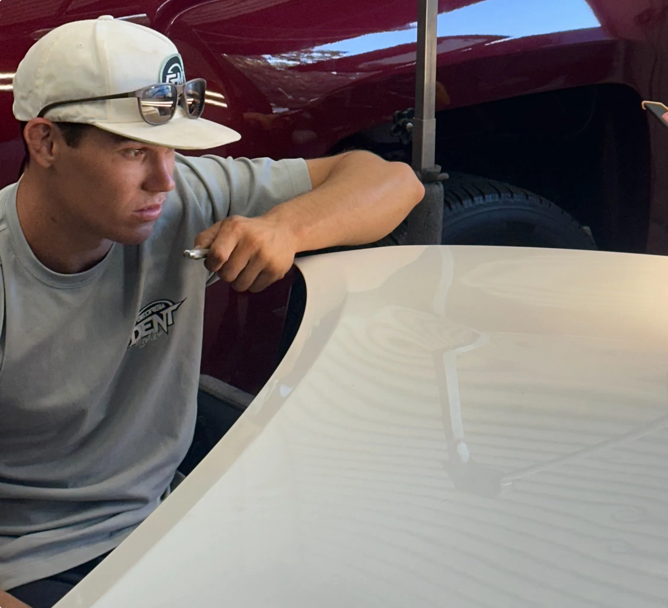 Dent on a car hood before paintless dent repair