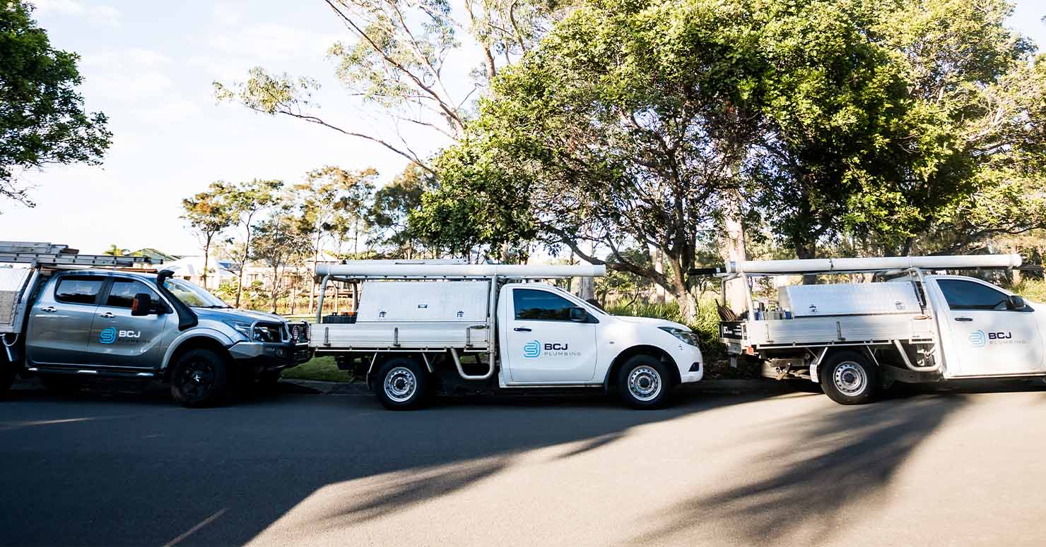 plumbing utes parked on side of road