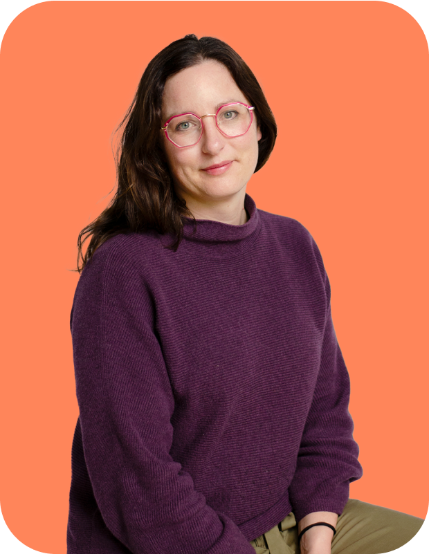 Image of Dr Alison Mant-Melville, Lead Data Scientist at Dot Loves Data. She is smiling at camera with her head slightly tilted, and wearing some circular pink/purple eye glasses. She is wearing a purple sweatert with arms hanging in middle of her legs, and body looking at camera. She is wearing a deep purple sweater and sitting down. The image is on an orange background. 