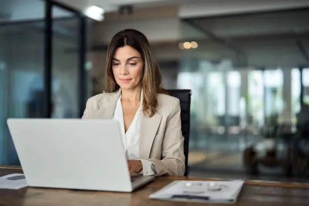 Mujer sentada frente a su computadora supervisando sueldos, pagos y obligaciones fiscales dentro de los servicios de nomina de la empresa.