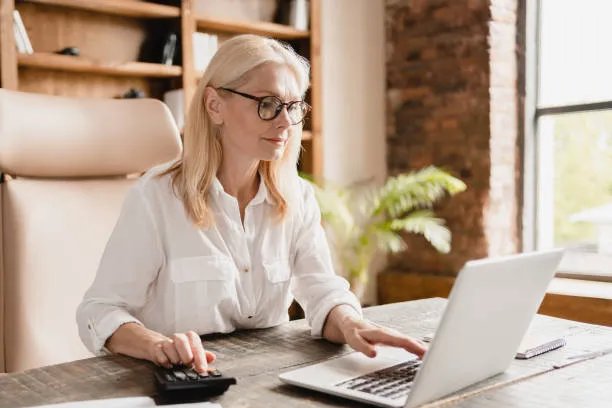Mujer con lentes revisando su computadora y controlando nómina de empleados de manera confiable dentro de la administracion nomina.