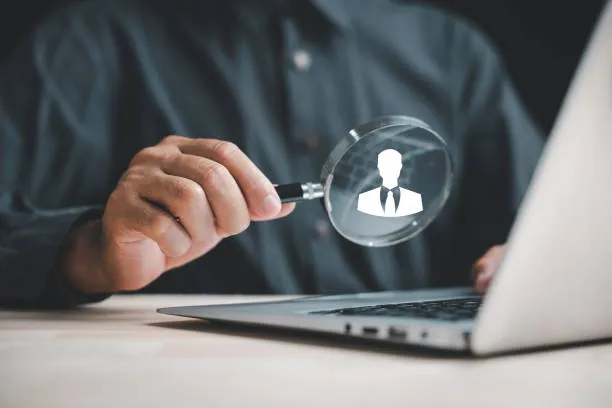 Hombre observando símbolo de persona con lupa, simbolizando análisis y control en la requisicion de personal