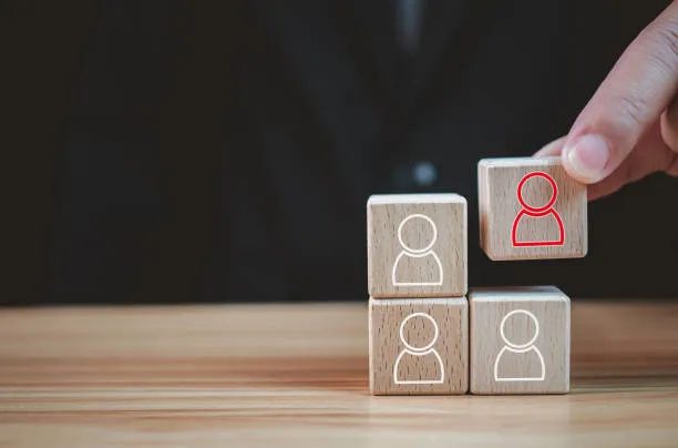 Cubos de madera con símbolos de personas, ilustrando organización y planificación en la requisicion de personal.