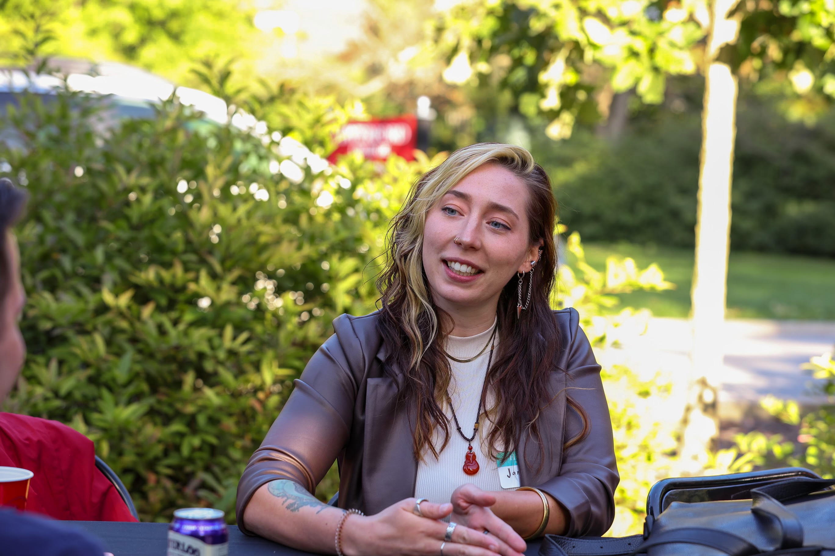 Jamie engaged in conversation with an interviewee, outside at a college campus during a sunny day