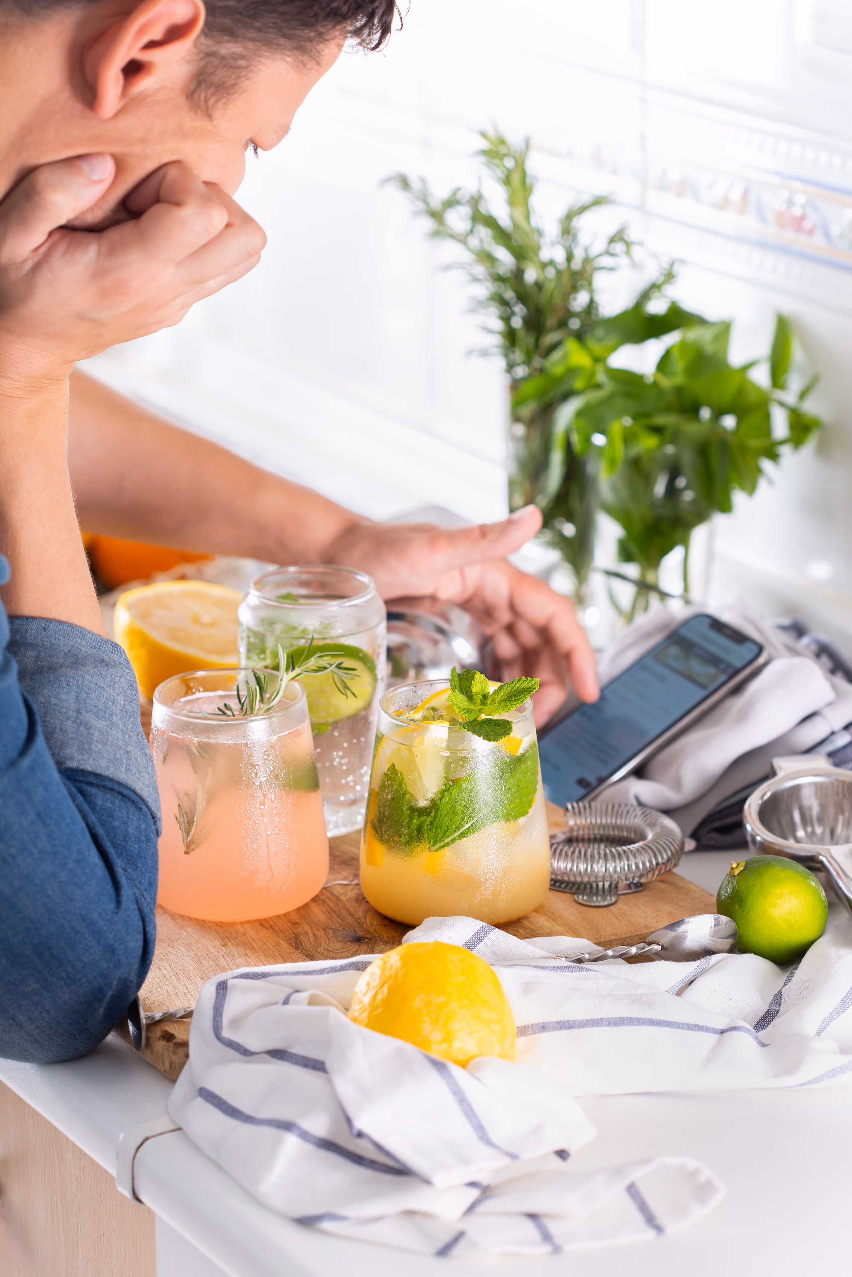 Man looking at a recipe on his phone while making a drink at home