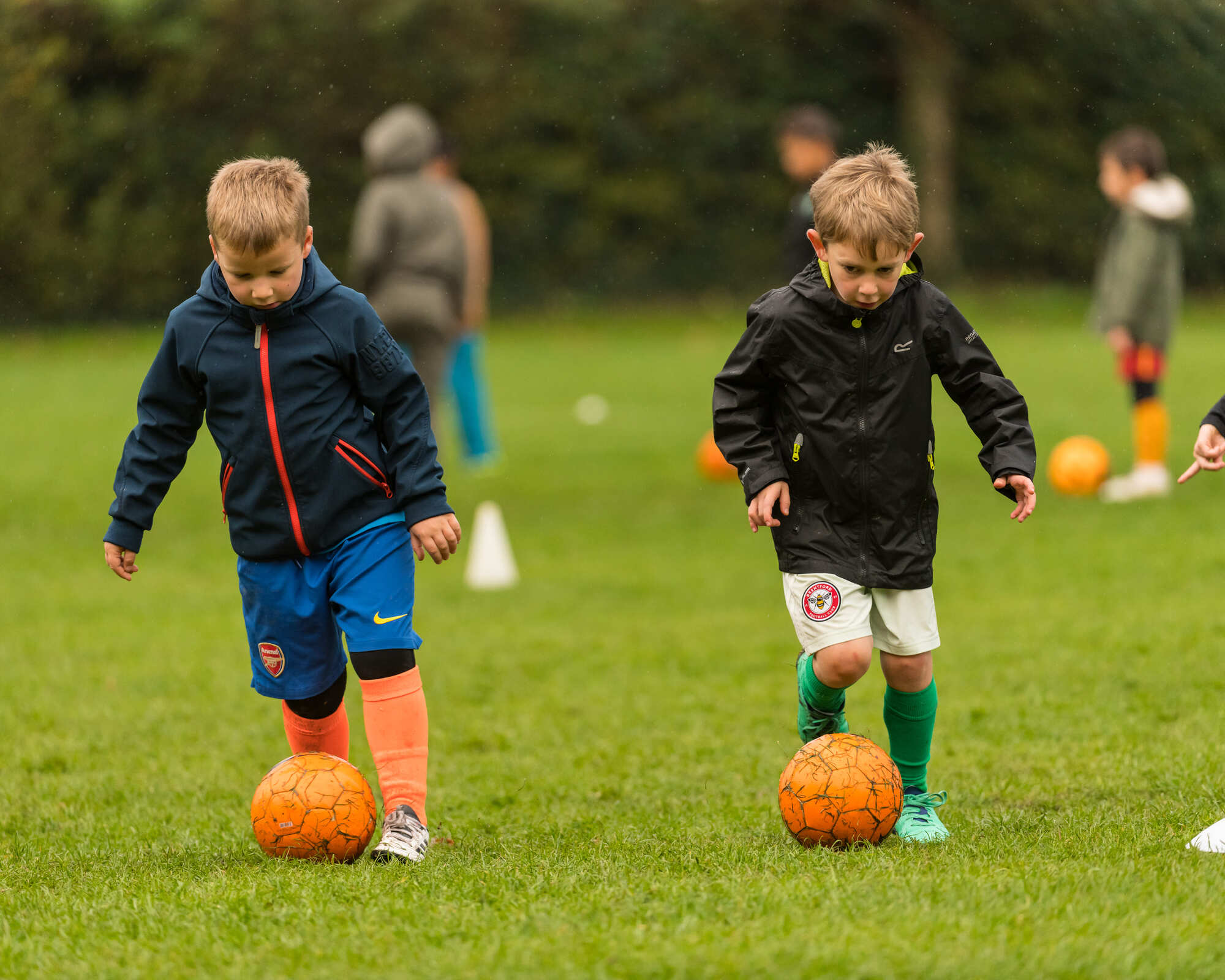 Young soccer players training on a lush green field, focusing on agility and ball control.