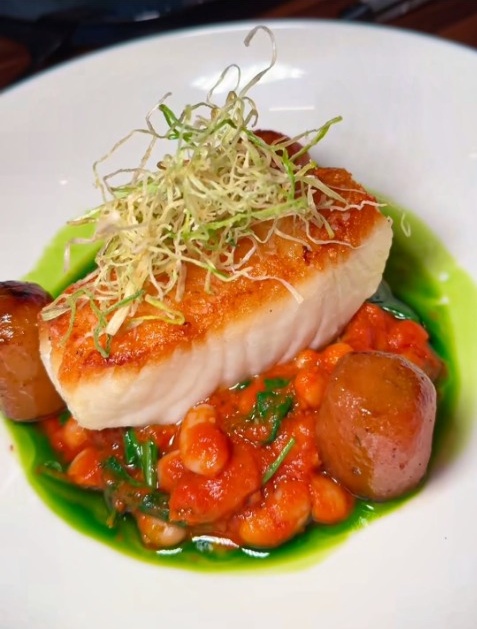 Pan-seared Chilean Sea Bass with golden crust over tender gigante beans at Duke's Steakhouse