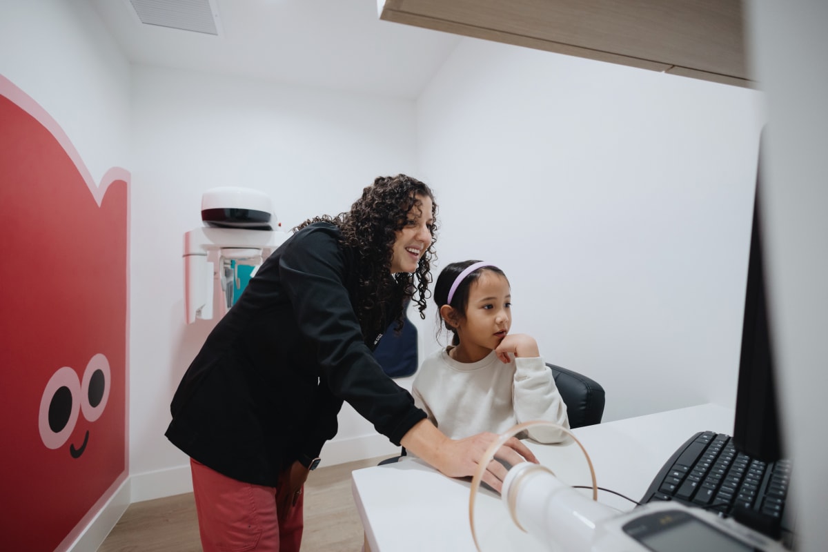 Pediatric dentist consulting with young patient at treatment chair