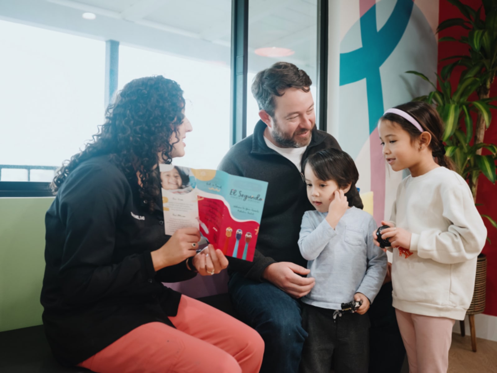 Dentist showing educational materials to parents and child in consultation