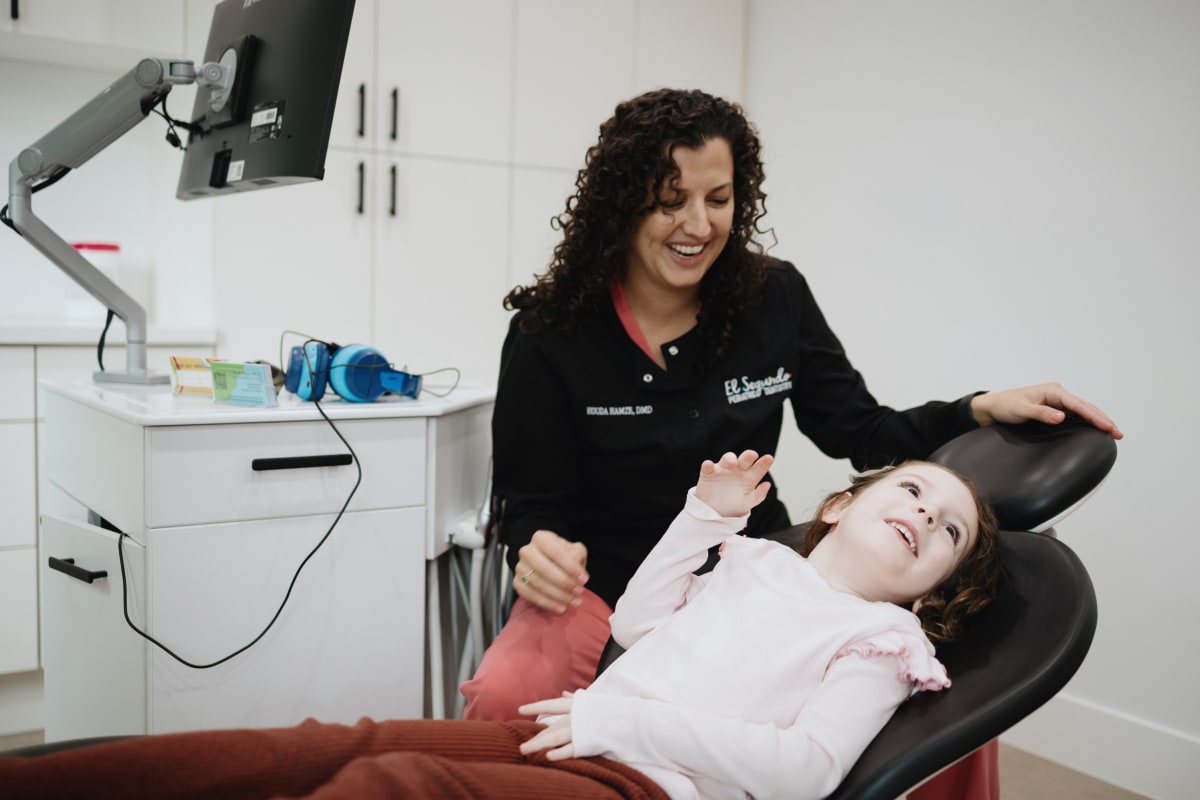 Pediatric dentist examining a young child in the dental chair during an evaluation