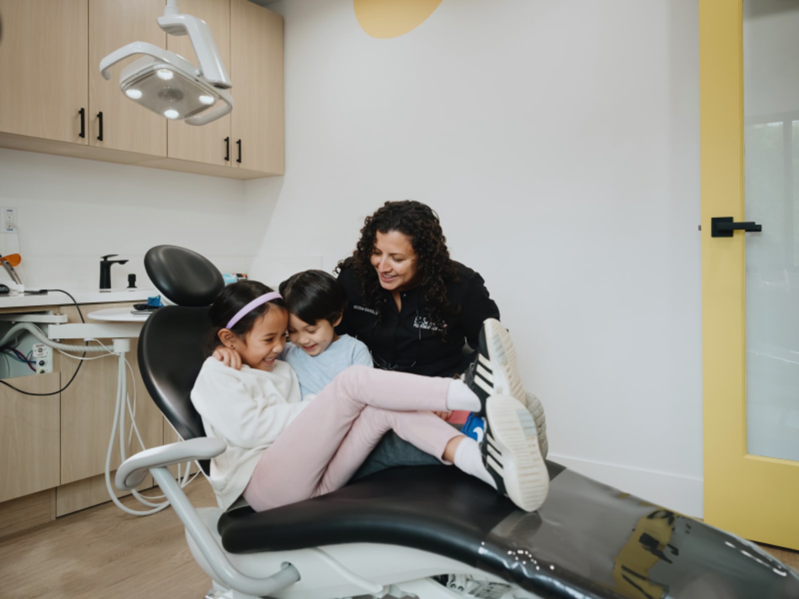 Dentist discussing findings with a parent while child sits in the dental chair